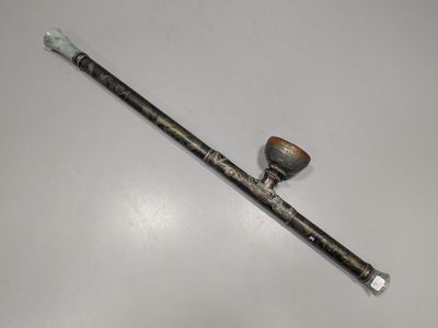 une vieille pipe posée sur une table blanche, à côté d'un bâton en bois