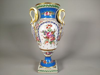 un vase bleu orné de fleurs, posé sur un socle