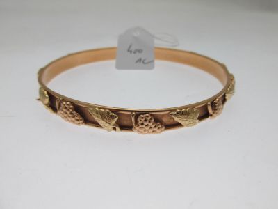 gros plan d'un bracelet en or sur une surface blanche