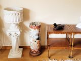 une petite table sur laquelle se trouve un vase, à côté d'une lampe