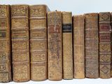 many old books lined up on a white surface