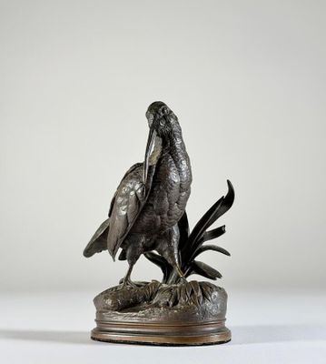 une statue en bronze représentant un oiseau posé sur un rocher, sur fond blanc