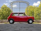 an old red mini car parked in front of a gate