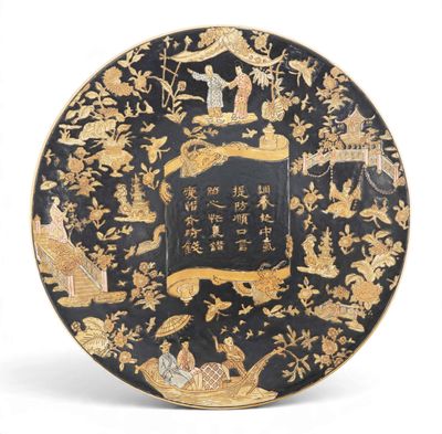 une image représentant une assiette noire et dorée ornée d'oiseaux et de fleurs