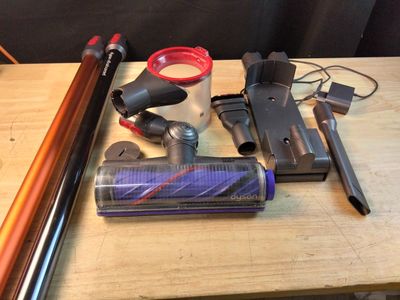plusieurs modèles différents d'aspirateurs et d'accessoires posés sur une table en bois