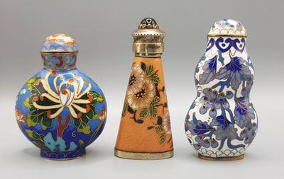 trois vases de couleurs différentes sont alignés sur une surface blanche