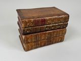 three old books stacked on top of each other on a white surface
