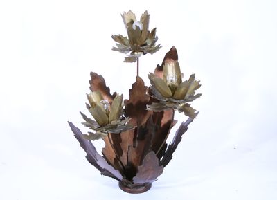 un vase en métal contenant des fleurs, posé sur une surface blanche