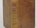 an old book sitting on top of a white table next to a white wall