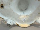 a white vase with a bird on it on a table