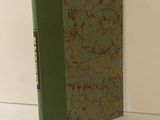 un livre à la couverture verte posé sur une table blanche