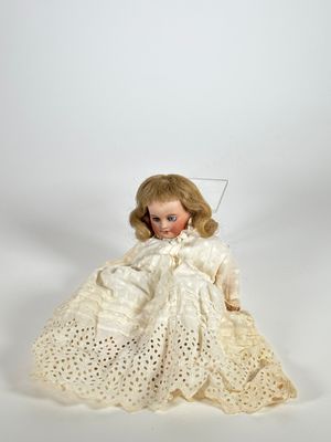 une image représentant une poupée vêtue d'une robe blanche et coiffée d'un chapeau blanc