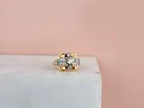 un gros plan d'une bague en or et diamants posée sur un bloc de marbre