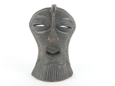 a black vase with a face on it on a white surface