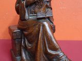 statue d'un homme assis sur un banc en train de lire un livre