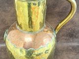un pichet en verre avec une anse dorée posé sur une table