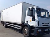 un camion blanc garé sur un parking, avec d'autres camions en arrière-plan