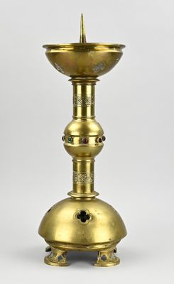 une lampe à huile ancienne en laiton posée sur un socle, sur fond blanc