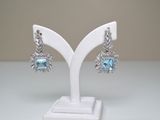 pair of blue topaz and diamond earrings on a white display stand