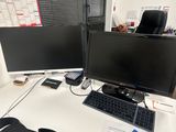 a black bag sitting on a desk next to two computer monitors