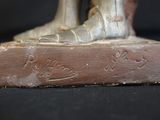 a bronze statue of a person standing on top of a book