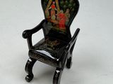 a miniature chair with a painting on the back of it