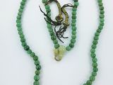 un collier de perles vertes avec un fermoir en forme de serpent et un collier de perles vertes avec un fermoir en forme de serpent