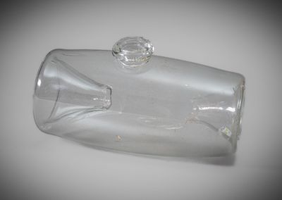 a clear glass bottle with a stopper sitting on a table