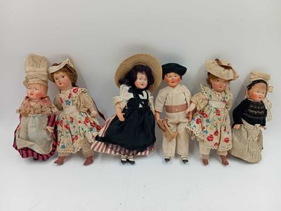 several dolls of different sizes and colors are lined up on a white surface