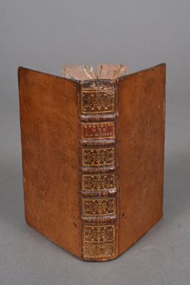 an old book sitting on top of a wooden table next to a gray wall