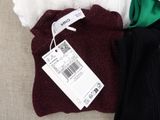 three pairs of sweaters on a couch with a price tag on them
