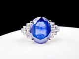 a close up of a blue sapphire and diamond ring on a white surface