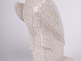 une statue de chouette blanche posée sur une table, à côté d'un vase