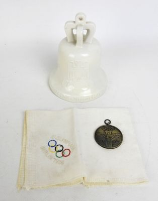 une clochette blanche ornée d'une médaille, posée à côté d'une serviette