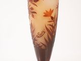 a tall glass vase with flowers and leaves on it