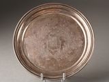 an antique silver plate with a design on it on a stand