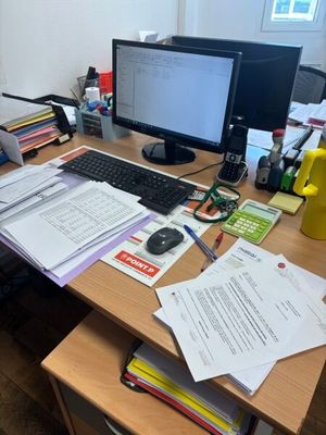 a desk with a computer and a lot of papers on it