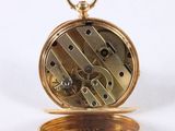 a close up of a gold pocket watch on a white surface