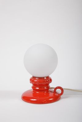 une lampe de table rouge surmontée d'une boule blanche