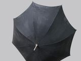 a black umbrella with a silver handle on a gray background