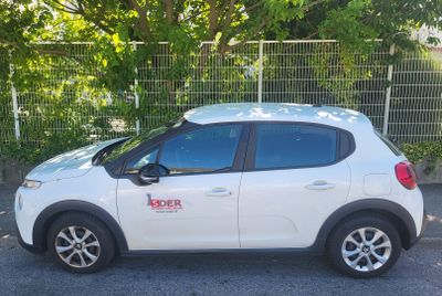 a picture of a white car parked in front of a fence