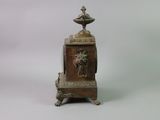 a small bronze clock with a bird on top of it