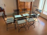 une table et des chaises en verre dans une pièce avec du parquet