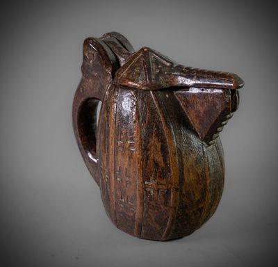 une image représentant une cruche en bois munie d'une anse, sur fond gris