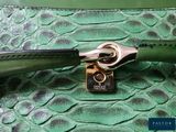 the handle of a green purse with a gold clasp on it
