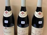 three bottles of wine sit on top of a wooden shelf