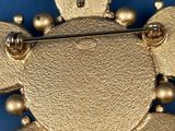 a gold brooch that is on a blue surface
