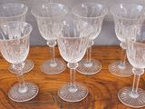 six clear wine glasses sitting on top of a wooden table