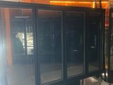a row of black refrigerators in a room with orange walls