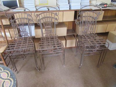 trois chaises en métal posées sur un sol recouvert de moquette, à côté d'une table